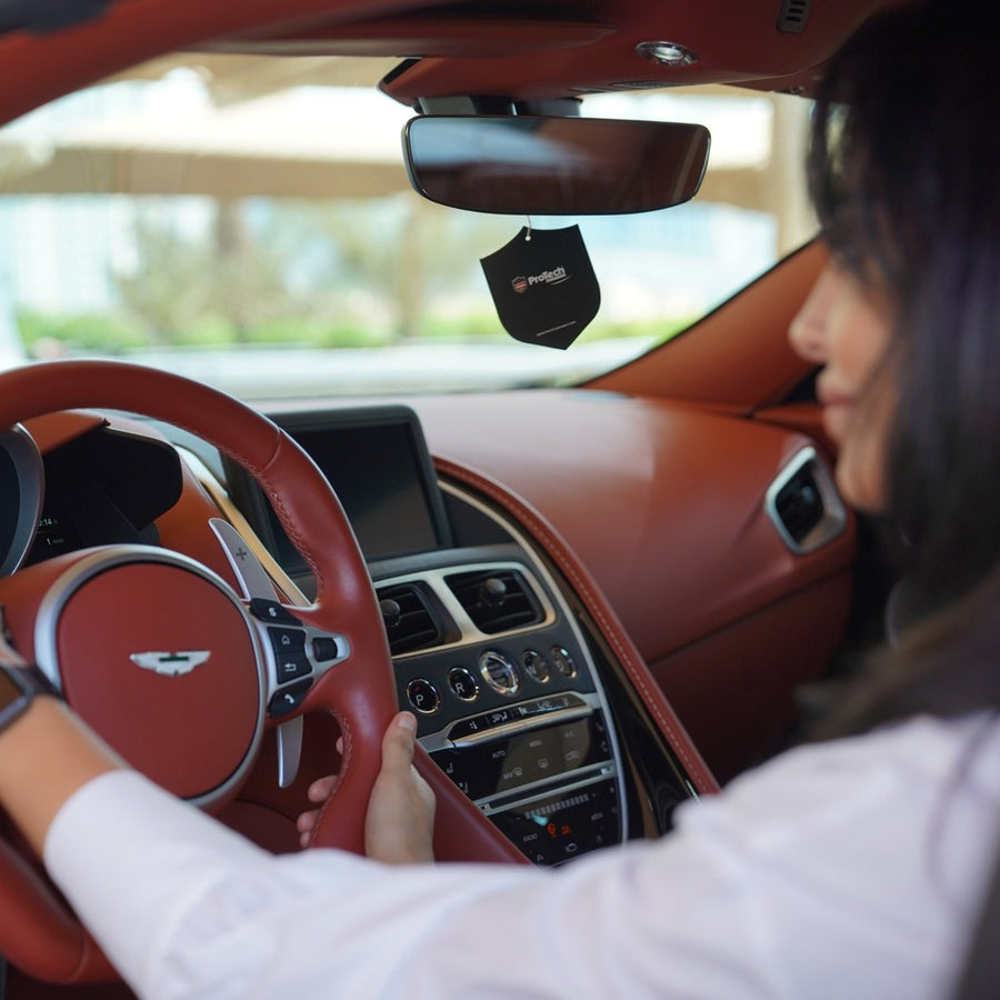 A customer enjoying a clean red leather interior, with the ProTech shield air freshener hanging from the mirror
